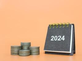 2024 escrivaninha calendário e pilha do moedas. a conceito do o negócio crescimento, financeiro investimento, mercado estoque, lucro retornar, dividendo e o negócio fundo dentro ano 2024 foto
