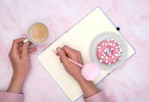 a menina calcula dentro uma caderno a calorias do uma rosquinha e uma copo do café foto