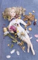uma quebrado porcelana boneca mentiras dentro a meio do seco flores abstrato destruição foto