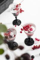 transparente Gin e tônico com gelo e fresco vermelho groselhas e Amora silvestre foto