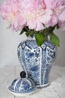 Rosa luxuoso peônias dentro a antigo chinês vaso com azul ornamento, primavera foto