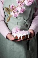 uma mulher decora uma caseiro Páscoa bolo com Rosa sakura flores, primavera Flor foto