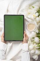 verde tela tábua, jovem mulher olhando para mãe dia presente on-line, tulipas foto