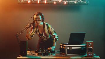 disco jóquei artista gritando às microfone, criando funky atmosfera durante moderno techno festa às Boate. mulher dj usando gira-discos para misturar Novo registros, estéreo equipamento. tripé tomada. foto