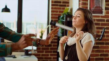 alegre amigos dançando às casa festa enquanto bebendo vinho copos, desfrutando celebração. multirracial grupo do pessoas tendo Diversão dentro de casa, fazendo divertido dança movimentos para música dentro moderno apartamento foto