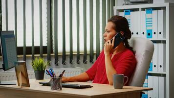 empregado falando em telefone dentro o negócio moderno escritório. hispânico empreendedor trabalhando dentro profissional área de trabalho, local de trabalho dentro pessoal corporativo companhia Falando em Smartphone olhando às computador Área de Trabalho foto