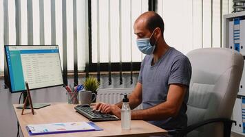 trabalhador vestindo proteção mascarar usando desinfetante gel durante coronavírus. empreendedor trabalhando dentro Novo normal escritório local de trabalho dentro companhia limpeza mãos usando antibacteriano álcool contra corona vírus. foto