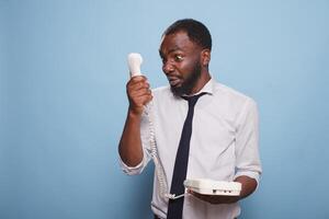 Bravo Preto homem de negocios gritando para dentro cordão telefone receptor, discutindo com pessoa em a de outros fim do a linha. ansioso africano americano empregado discutindo com Gerente em a telefone. foto