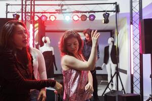 mulheres dançando e festa às social encontro dentro Boate iluminado com etapa holofotes. menina balada e tendo Diversão em pista de dança, desfrutando vida noturna lazer atividade foto