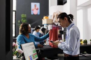 africano americano cliente pagando para à moda vestir, em pé às contador escrivaninha dentro roupas loja. viciado em compras africano americano mulher compras para elegante roupas dentro moderno boutique. moda conceito foto