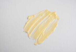 produtos cosméticos textura de mancha amarela cremosa em um fundo branco. a textura da máscara de cabelo de cosméticos naturais, creme, esfoliante foto