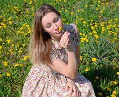 uma menina dentro uma vestir dentro uma compensação com dente-de-leão. a menina entre a flores foto