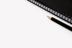 Preto lápis com Preto espiral caderno em branco fundo. foto