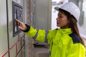 ásia elétrico engenheiro segurando prancheta para verificação e monitoramento a elétrico sistema dentro a ao controle sala, técnico Tailândia pessoas trabalhando foto