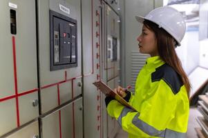 ásia elétrico engenheiro segurando prancheta para verificação e monitoramento a elétrico sistema dentro a ao controle sala, técnico Tailândia pessoas trabalhando foto