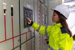 ásia elétrico engenheiro segurando prancheta para verificação e monitoramento a elétrico sistema dentro a ao controle sala, técnico Tailândia pessoas trabalhando foto