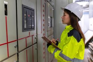 ásia elétrico engenheiro segurando prancheta para verificação e monitoramento a elétrico sistema dentro a ao controle sala, técnico Tailândia pessoas trabalhando foto