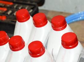 branco plástico latas com vermelho tampas. latas do transmissão óleo foto