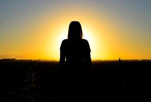 a figura do uma mulher às pôr do sol. Preto silhueta do uma mulher. foto