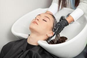 cabeleireiro lavando cabelo do uma mulher dentro uma beleza salão foto