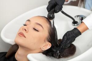 cabeleireiro lavando cabelo do uma mulher dentro uma beleza salão foto