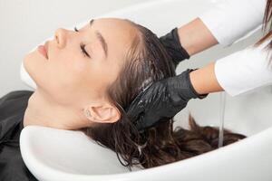 cabeleireiro lavando cabelo do uma mulher dentro uma beleza salão foto