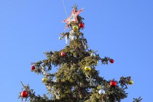 decorações Novo ano árvore. ouropel e brinquedos, bolas e de outros decorações em a Natal Natal árvore em pé dentro a aberto ar. foto