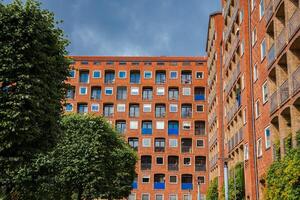 contemporâneo tijolo apartamento complexo dentro Escandinávia, cercado de vegetação foto