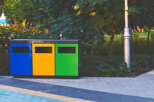 ecologia. separado desperdício containers para plástico, papel e vidro dentro uma verão parque foto