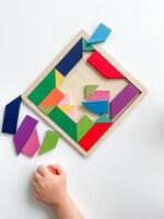 criança mão coleta multicolorido de madeira mosaico em branco fundo. foto