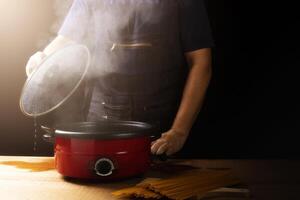 a chefe de cozinha faz espaguete dentro uma Panela dentro a cozinha, a atmosfera é rústico. molecular gastronomia livre espaço para anúncio, preto, Sombrio fundo. foto