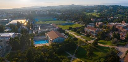 dourado hora aéreo Visão do ucla campus com gótico arquitetura, exuberante vegetação, e natação piscina foto