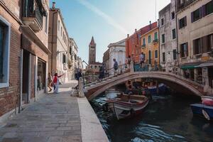cênico limitar canal dentro Veneza, Itália com tradicional arquitetura e barcos foto