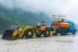 pesado estrada equipamento para deslizamento de terra ajuntar carrinhos de a beira da estrada dentro uma montanhoso área durante tormentoso clima foto