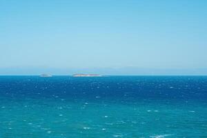 marinha em uma ventoso ensolarado dia com ilhas e distante por muito pouco visível costa em a horizonte foto