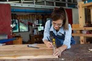 jovem mulher é Treinamento para estar uma carpinteiro dentro oficina. carpinteiro trabalhando com equipamento em de madeira mesa. mulher trabalho dentro uma carpintaria fazer compras. foto