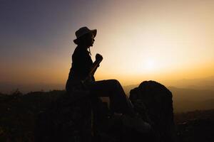 silhueta da mão de uma mulher cristã rezando, mulher rezando pela manhã no fundo do nascer do sol. espiritualidade e religião, mulher orando a Deus. conceito de cristianismo. foto