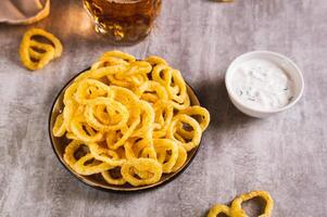 caseiro frito cebola argolas em uma prato e molho em a mesa foto