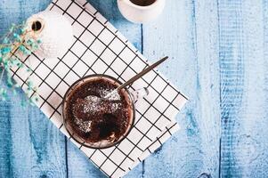 chocolate Bolinho com em pó açúcar dentro uma caneca em a mesa topo Visão foto