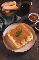 Tiramisu bolo fez do biscoitos, delicado creme e café em uma prato em a mesa vertical Visão foto