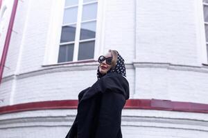 lindo mulher dentro lenço de cabeça dentro retro estilo caminhando baixa a rua foto