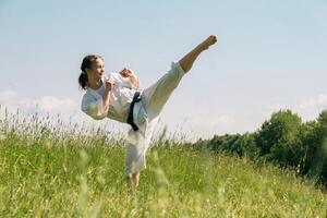 adolescente menina Treinamento karatê kata ao ar livre, executa a mawashi geri pontapé foto