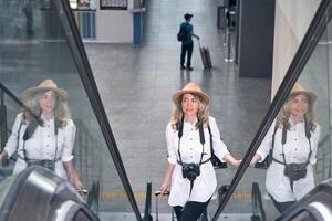 mulher viajante sobe a escada rolante às a aeroporto foto