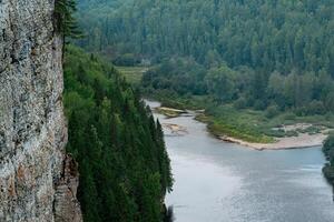 montanha rio entre arborizado bancos, Visão a partir de a topo do a penhasco, a usva rio dentro a permanente krai, Rússia foto