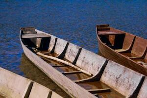 tradicional de madeira fundo chato barcos em a rio banco, rural panorama foto