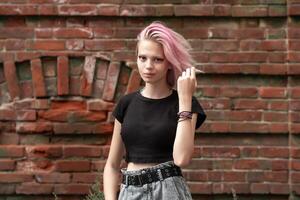 retrato do uma Adolescência menina com Rosa cabelo em uma tijolo parede fundo foto