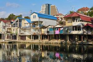 a banco do a dagomys rio é construído acima com pequeno chalés com garagens para barcos dentro sóbrio, Rússia foto