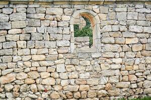 pedra parede do a antigo construção com uma semicircular janela, além que de outros ruínas estão visível foto