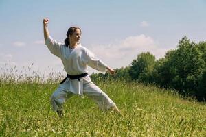 adolescente menina praticando karatê kata ao ar livre dentro kokutsu-dachi posição foto