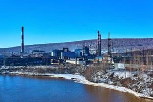 inverno industrial panorama com a velho Coca e químico plantar em a rio banco foto